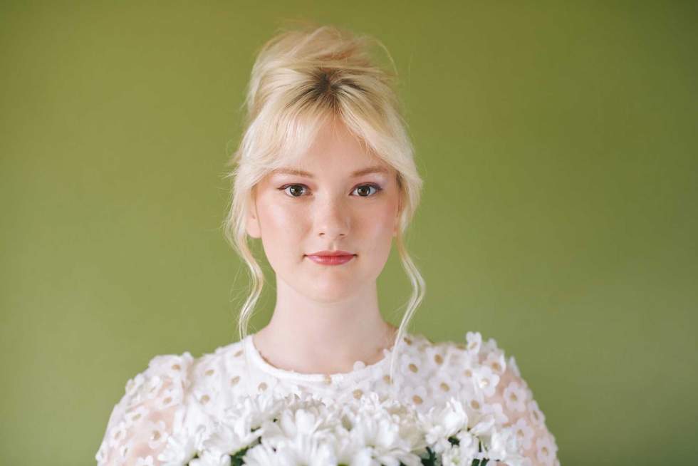 Beauty portrait of pretty young 15 - 16 year old teeenage girl wearing white dress posing on green background