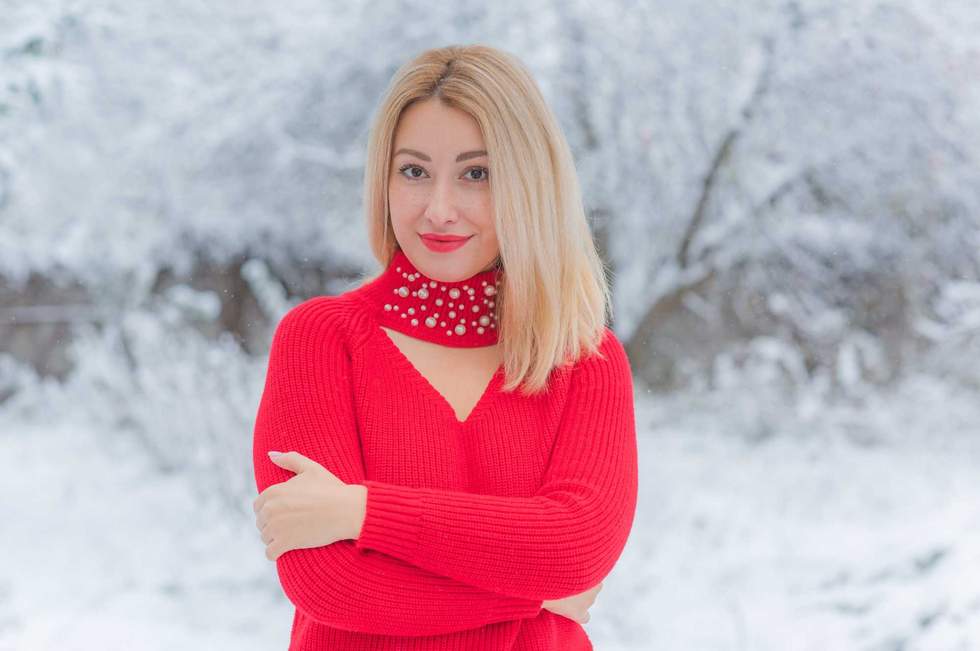Blonde lady in warm wool clothes at snowy day outdoor. Romantic style
