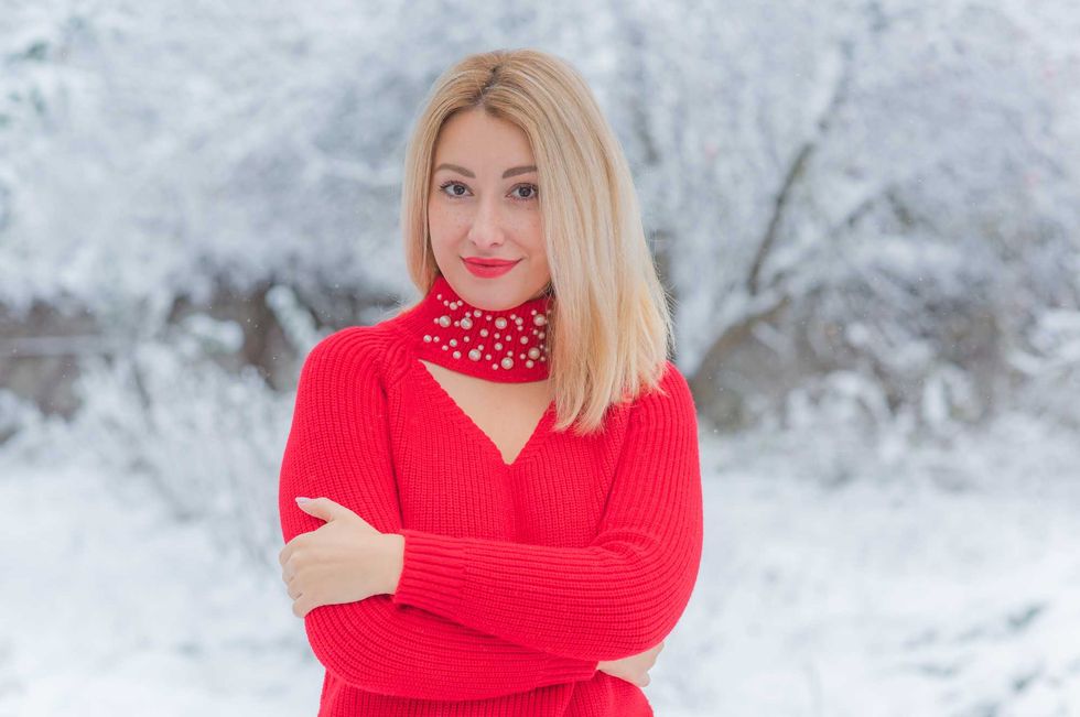 Blonde lady in warm wool clothes at snowy day outdoor. Romantic style