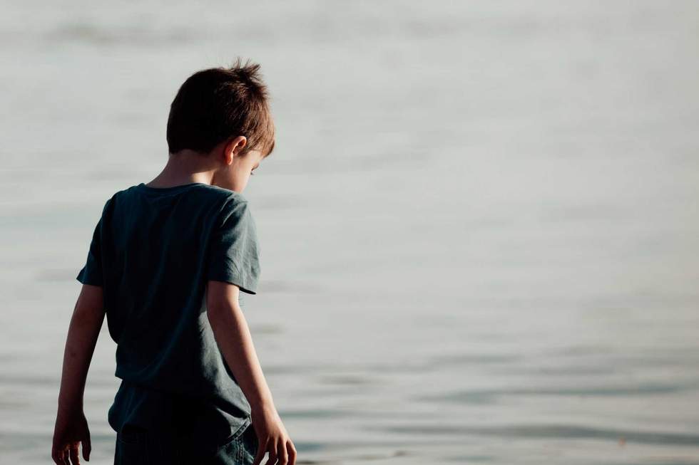 Boy, 5 years old, back to camera with beach water in background - copy space.