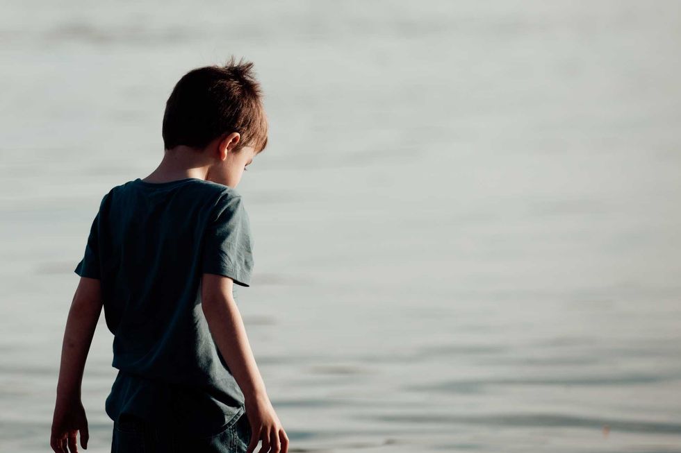 Boy, 5 years old, back to camera with beach water in background - copy space.