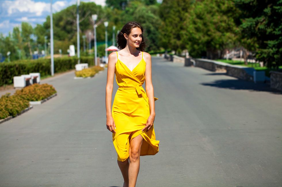 close up portrait of a young blonde woman in yellow dress walking in summer park