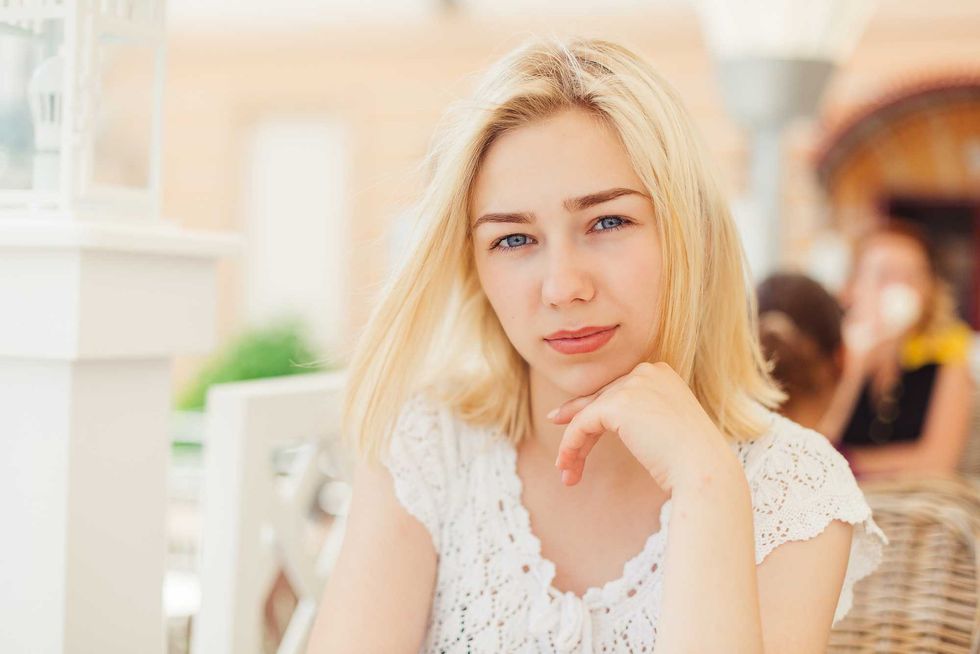 Close up portrait of toyng blondie girl sitting in outdoor cafe in summer. Leisure summer time and lifestyle of student girl