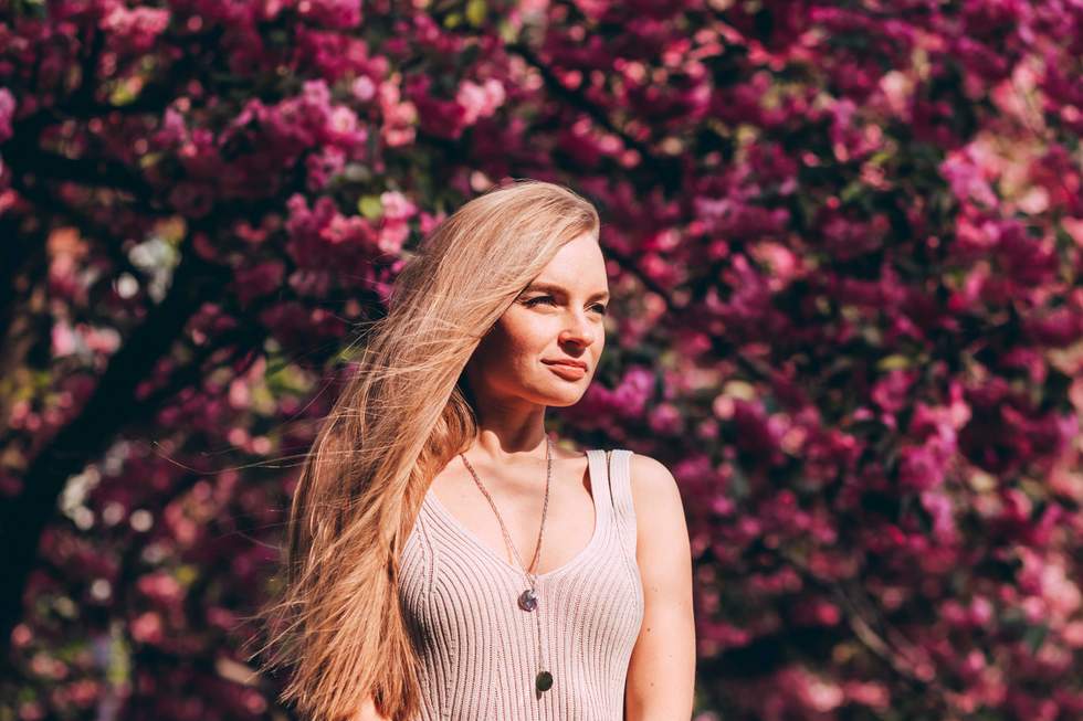 Closeup portrait of a lovely girl in a park with blooming Japanese sakura trees. 