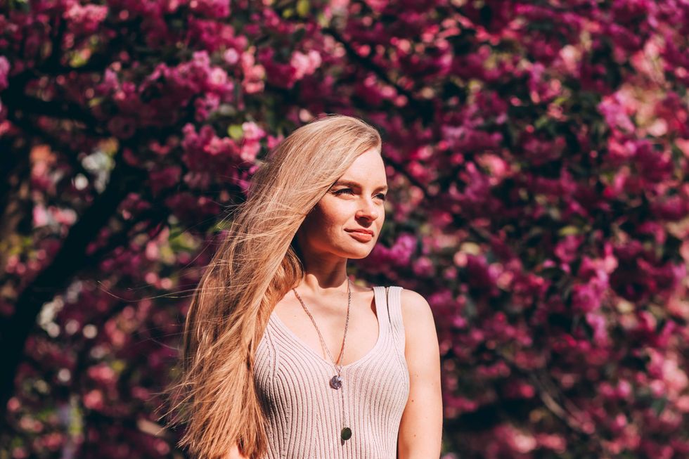 Closeup portrait of a lovely girl in a park with blooming Japanese sakura trees.