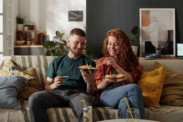 couple eating takeout on a couch