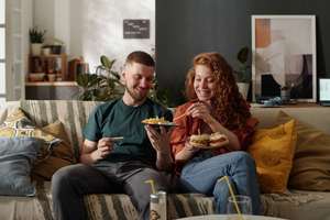 couple eating takeout on a couch