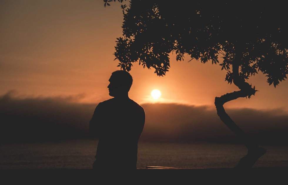 Dark silhouette of a man admiring the sunset from a Miraflores viewpoint over the Pacific Ocean in Lima, Peru.