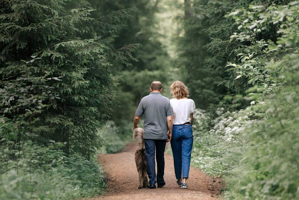 family walking in the forest with their dog, rear view