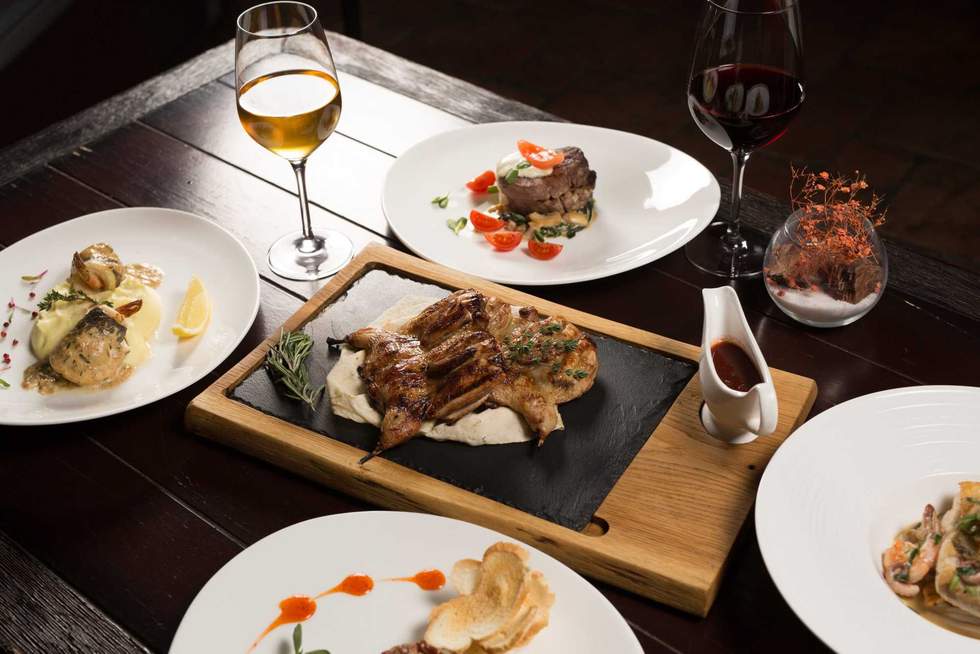 Grilled partridge, sea bass, Tartarus. Different dishes on the table in the restaurant.