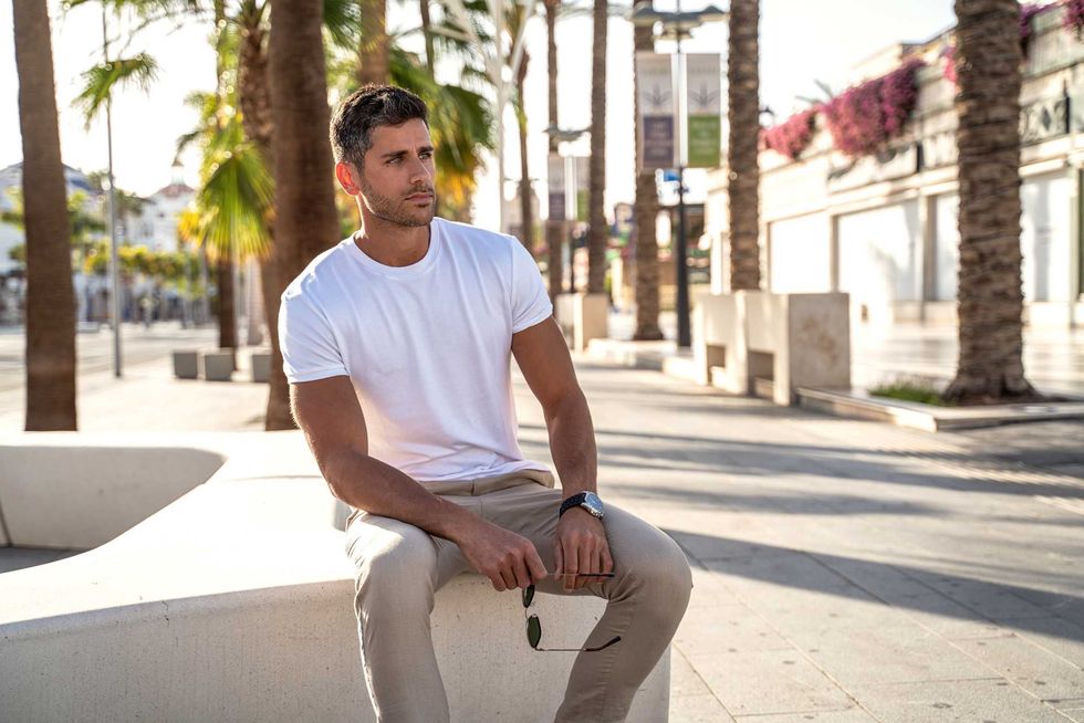Handsome young man wearing white tshirt posing on city street background. Casual style. Fashionable guy. Summer vibes.