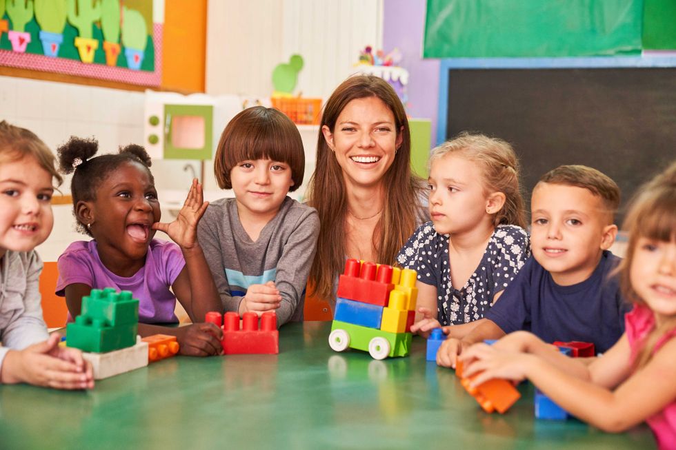Happy children in preschool or in international kindergarten with a kindergarten teacher
