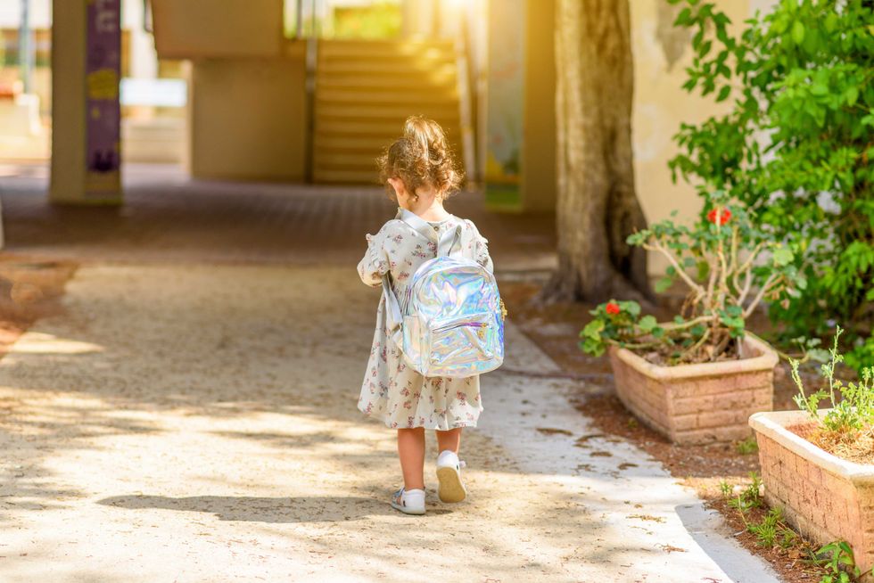 Happy kid back to school. Little girl with backpack go to elementary school. Child of primary school.Back view of pupil going to school for the first time.