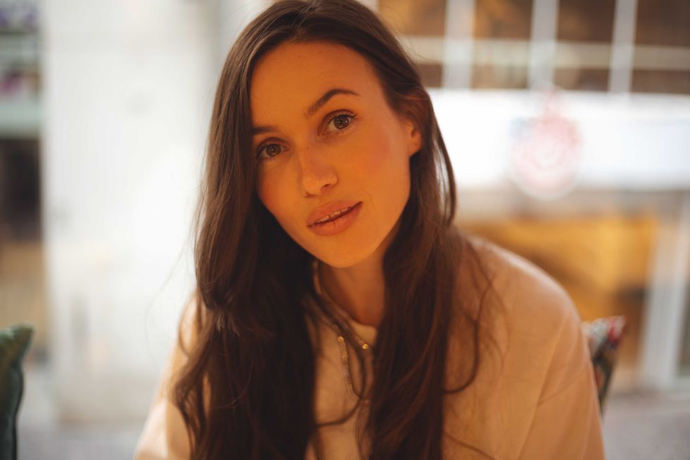 Long hair brunette woman close up sitting in cafe, have a rest. Portrait of woman look sensual, dreaming or flirty. Girl look at camera