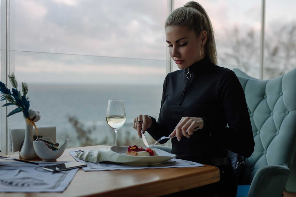 Luxury woman eating cake in restaurant with sea view