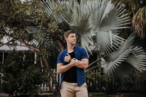 man standing in front of a palm tree