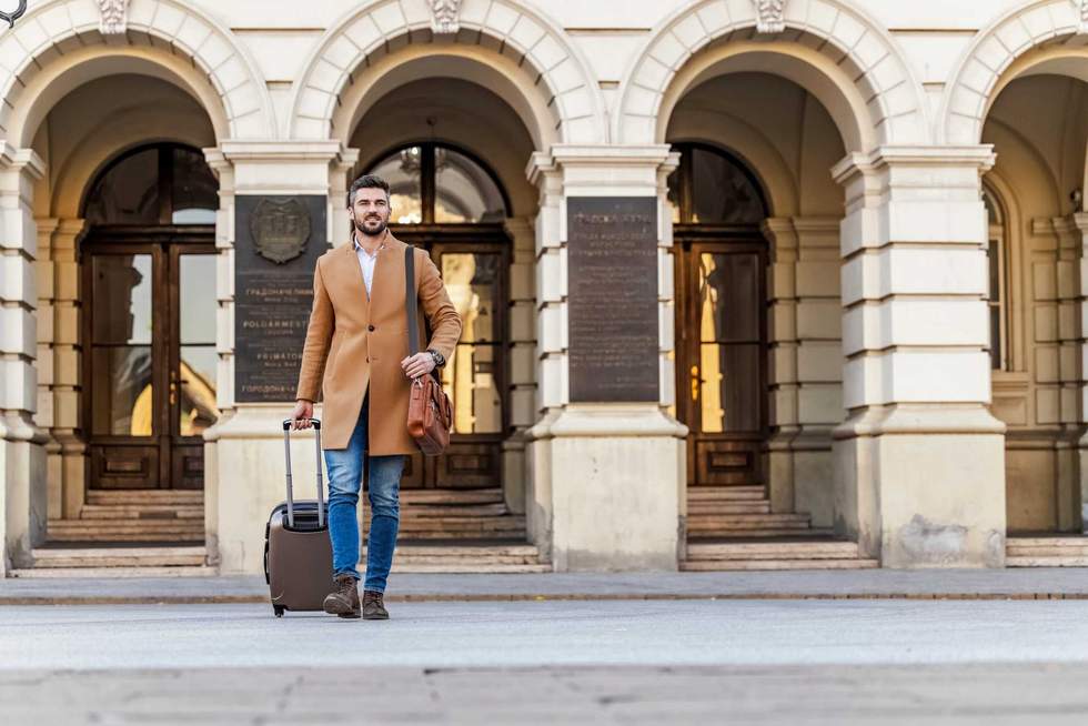 Man walking in a urban street with suitcase. Business trip.