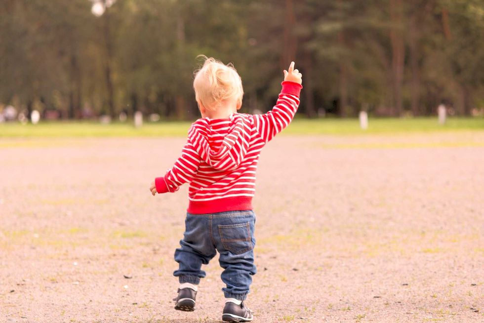One year toddler running in the autumn park. Back view.