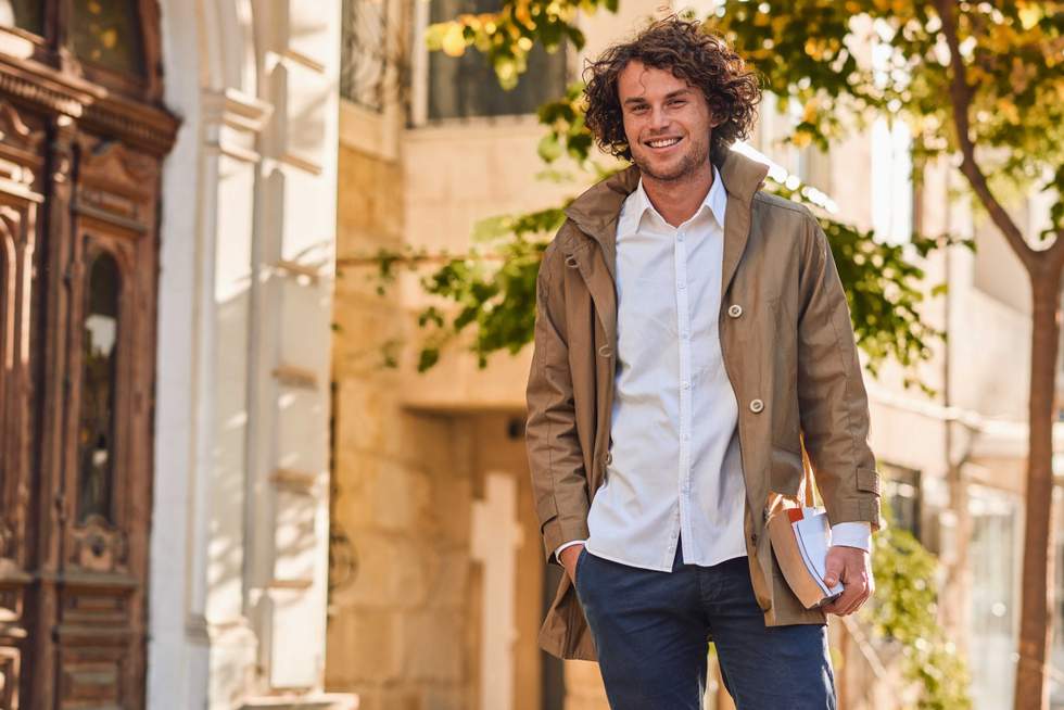 Outdoor image of handsome young man with books outdoors.