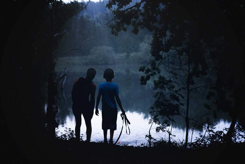 people are looking in the woods and on the riverbank. Adventures of teenagers