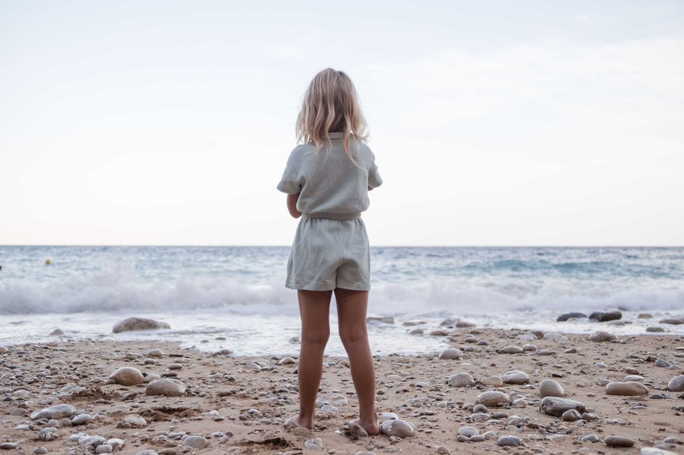 pictured above is a little girl standing on a beach