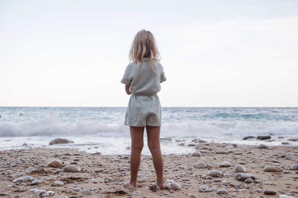 pictured above is a little girl standing on a beach