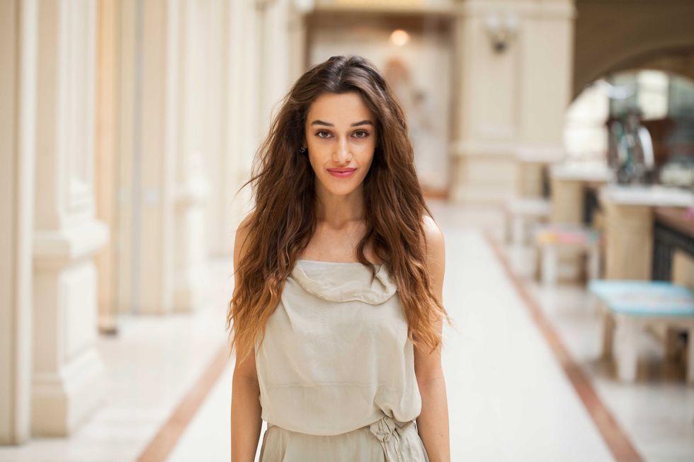 Portrait close up of young beautiful brunette woman in beige dress walkin in the shop