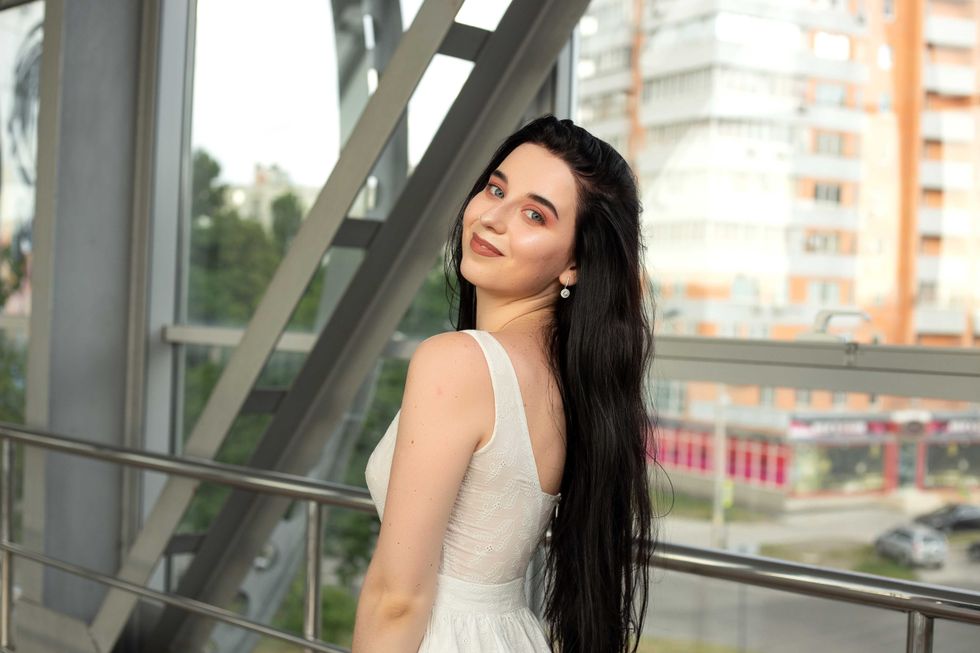 Portrait of a beautiful brunette in a light dress on the street in a pedestrian crossing on a summer day