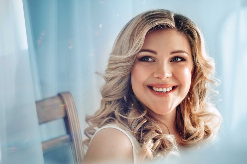 portrait of a beautiful smiling woman with blond hair on a blue background