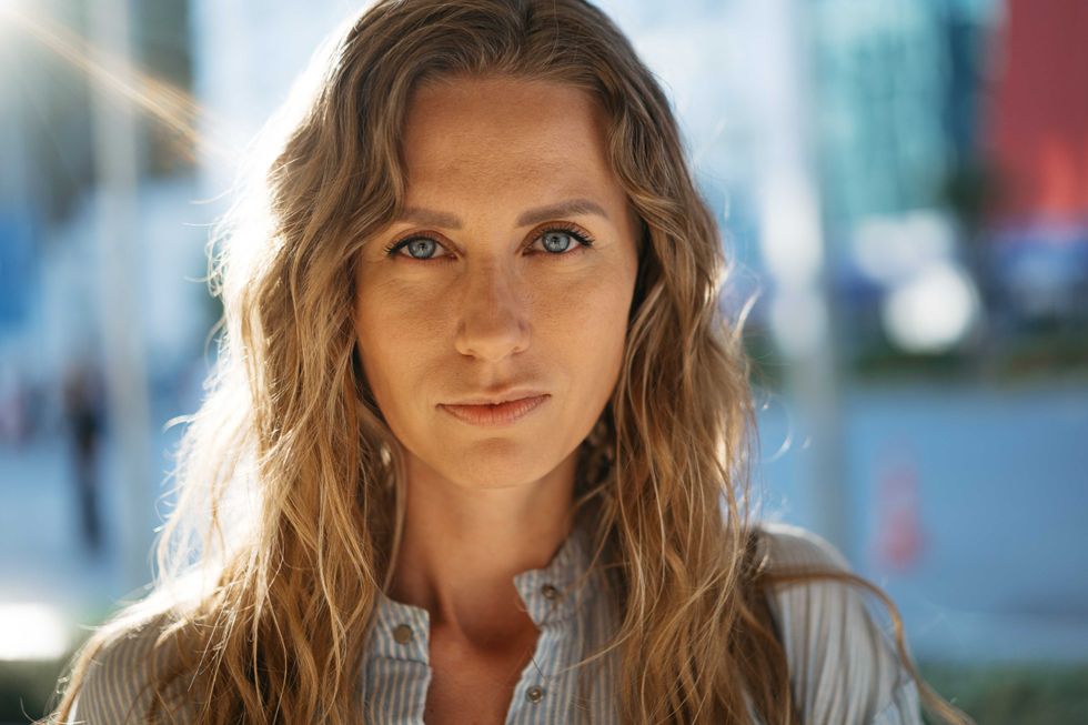Portrait of a charming young woman posing for camera in the city, close up