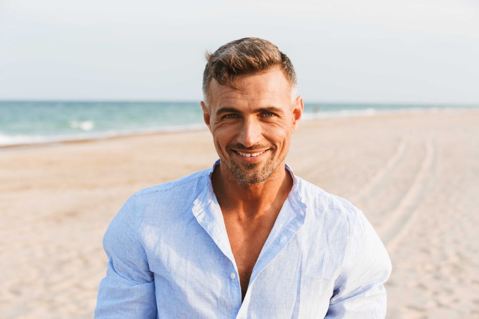 Portrait of a handsome smiling man in shirt standing at the beach