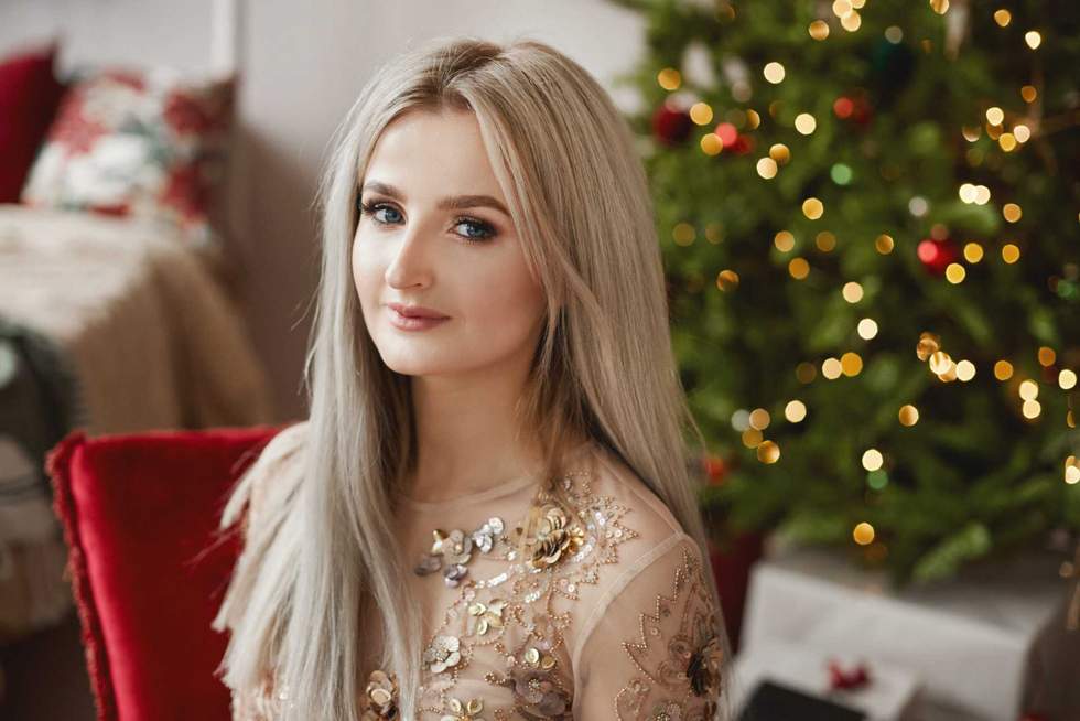 Portrait of a model girl with platinum blond hair with festive Christmas lights at the background.