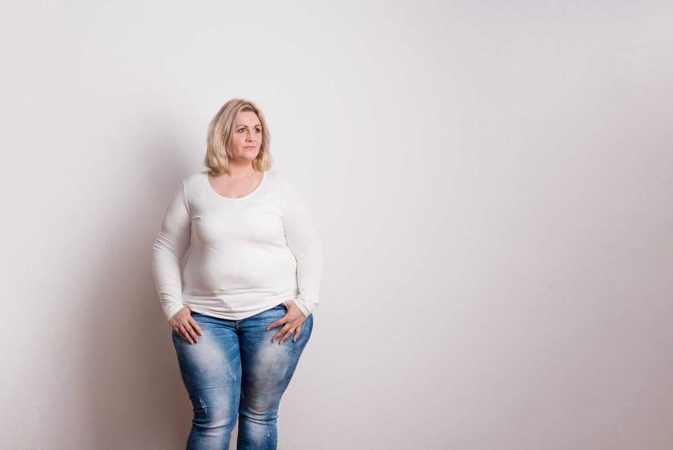 Portrait of an attractive blond overweight woman in studio on a white background. Copy space.
