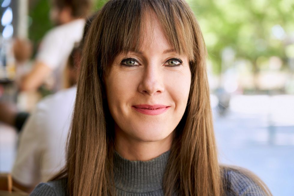 Portrait of attractive happy young woman looking at camera on cafeteria terrace.