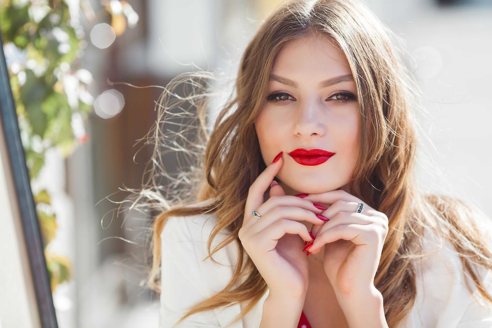 Portrait of attractive young girl outdoors. Beautiful urban lady smiling at camera. Female with red lips.