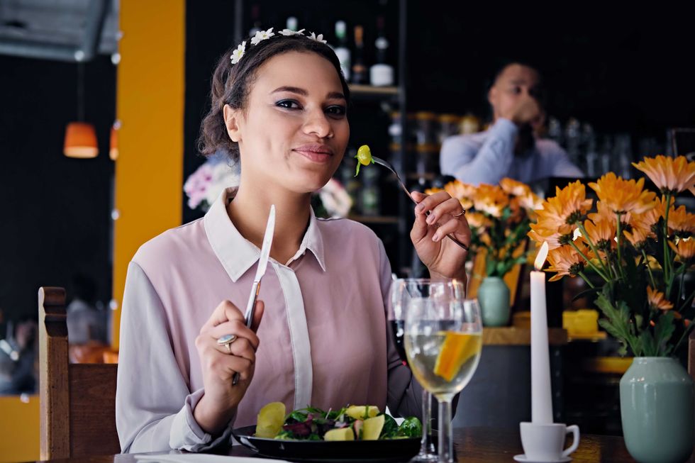 Portrait of one black American female eats gourmet vegetarian meal and drinks wine in a restaurant