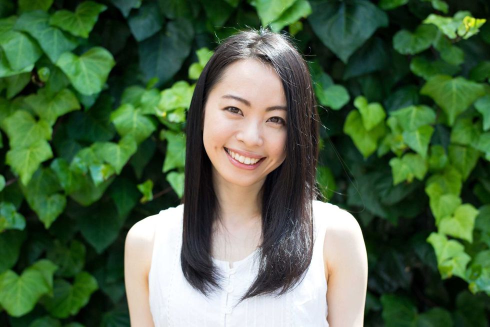 pretty asian woman smiling in front of ivy