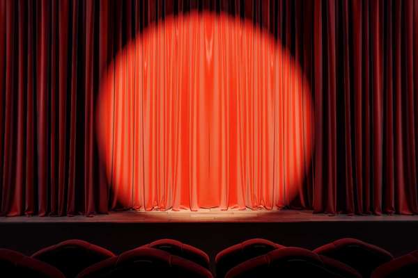Red stage with spot light on empty drawn curtains. Show concept.