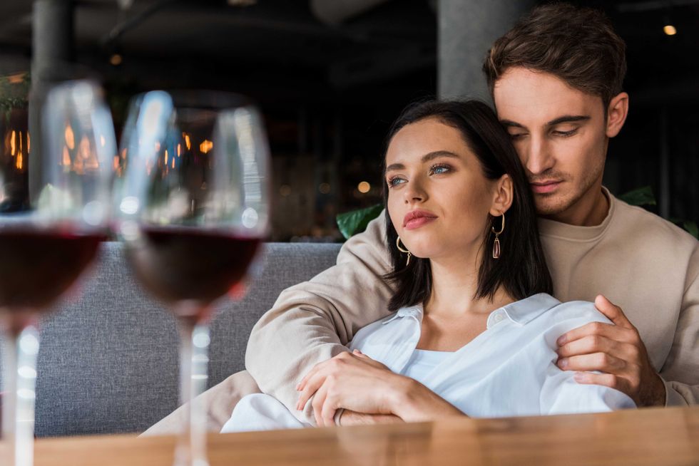 selective focus of man and woman sitting in restaurant near glasses with red wine