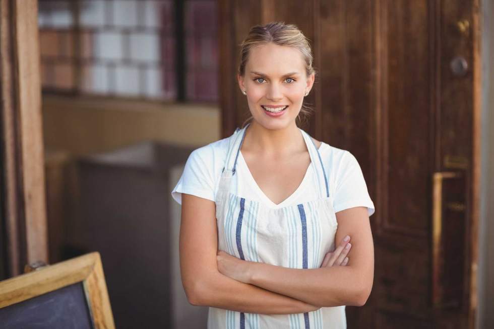 Smiling blonde waitress with arms crossed