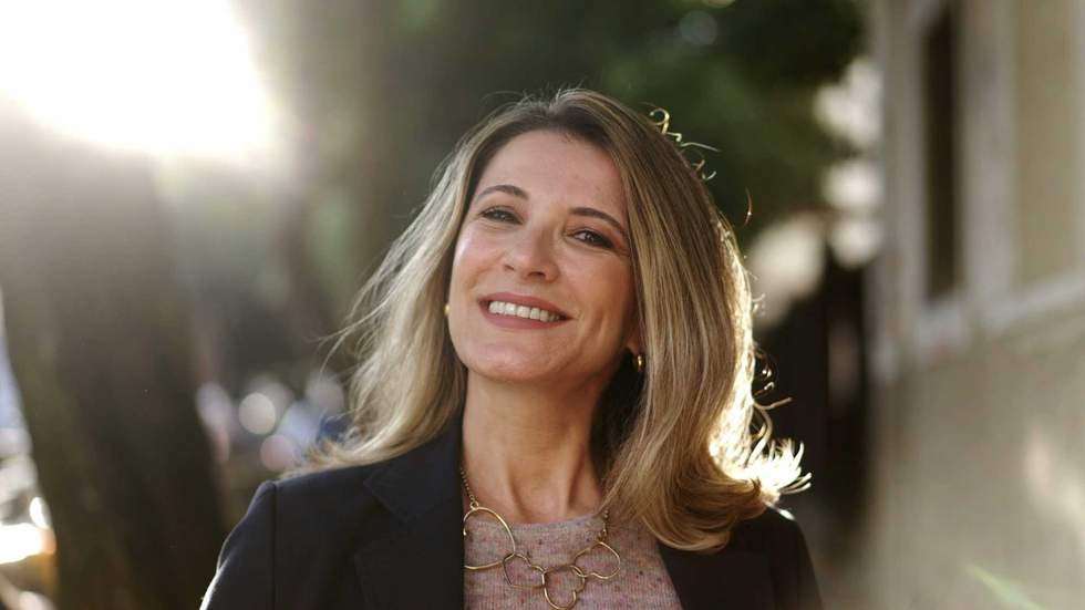 Smiling confident older woman walking outdoors with sun backlight. Proud mature lady walks forward face closeup