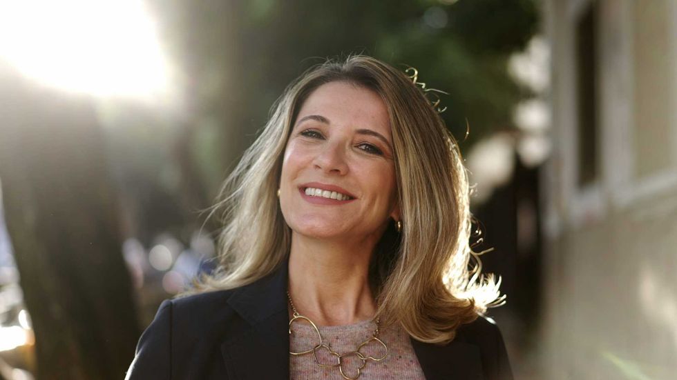 Smiling confident older woman walking outdoors with sun backlight. Proud mature lady walks forward face closeup