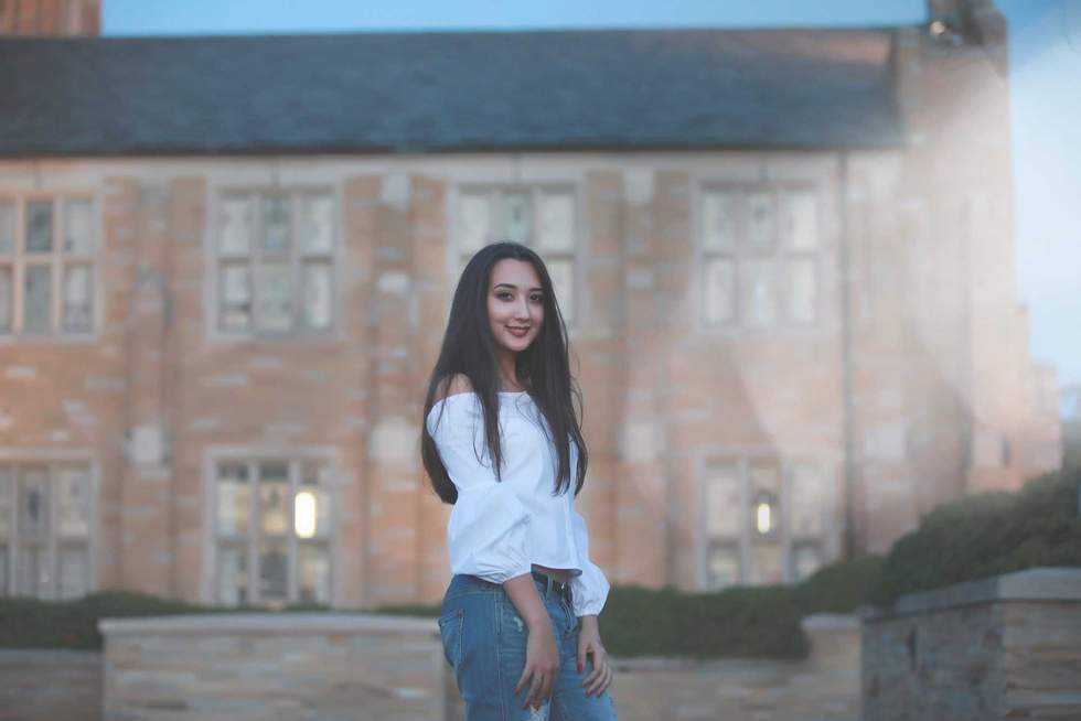 Smiling elegant woman standing on background of big house.