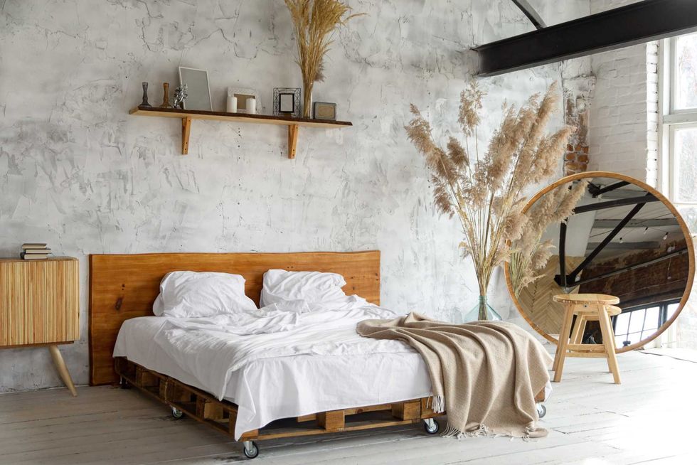Spacious airy white eco style loft bedroom with bed, mirror and pampas grass decoration