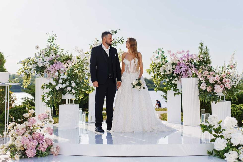 The bride and groom at the wedding ceremony site, decorated with flowers and white columns, in the park. the delicacy of the decor of flower arrangements, natural and artificial flowers.