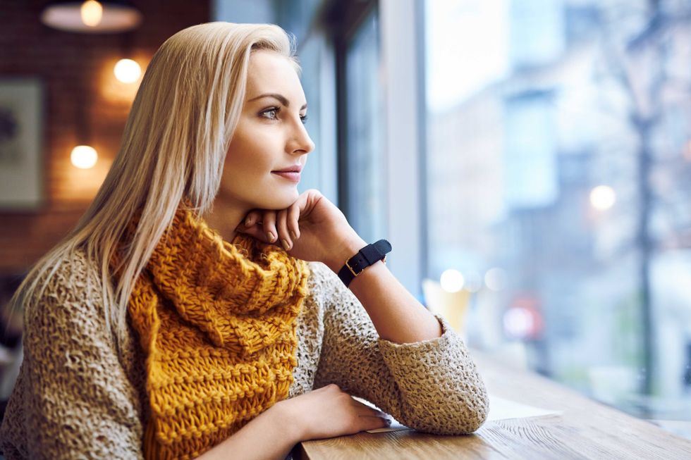 thoughtful young woman looking through window in a cafe during winter day
