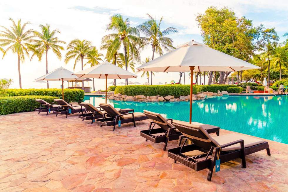 Umbrella and chair around swimming pool in resort hotel for leisure travel and vacation neary sea ocean beach at sunset or sunrise time
