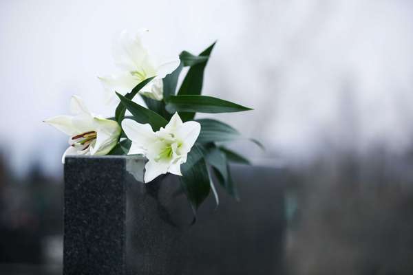 White lilies on black granite tombstone outdoors