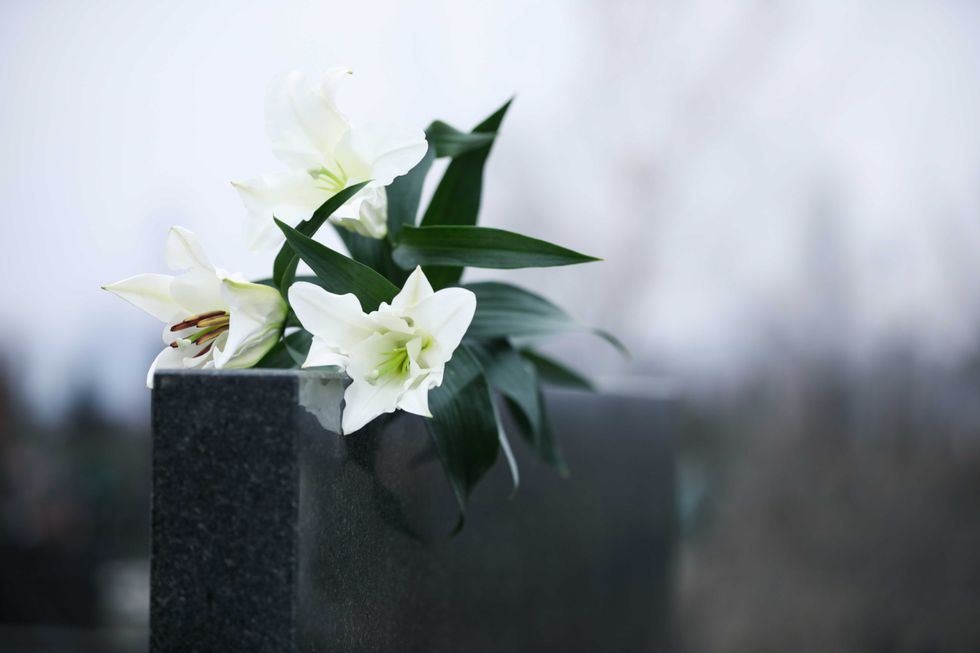 White lilies on black granite tombstone outdoors
