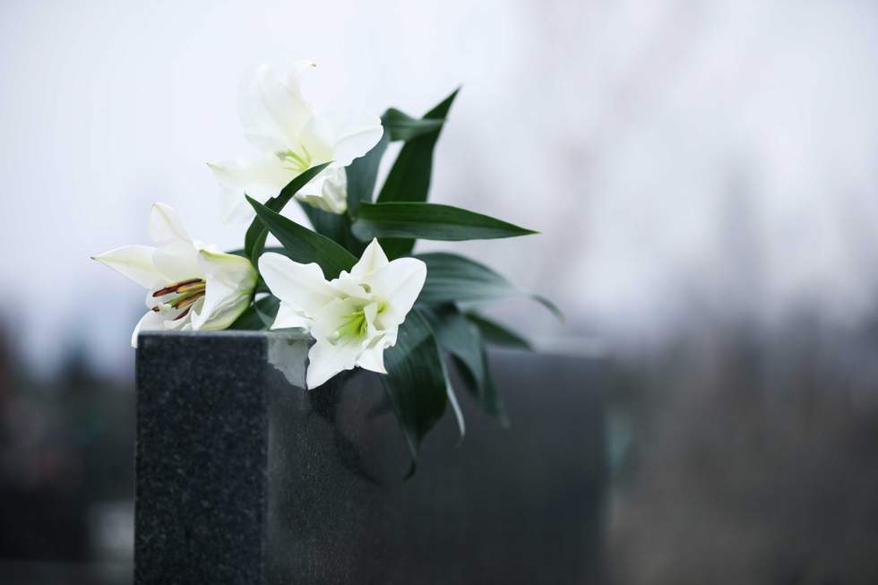White lilies on black granite tombstone outdoors